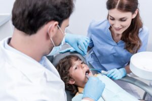 dentists treating teeth of little patient in dentist chair in Naples